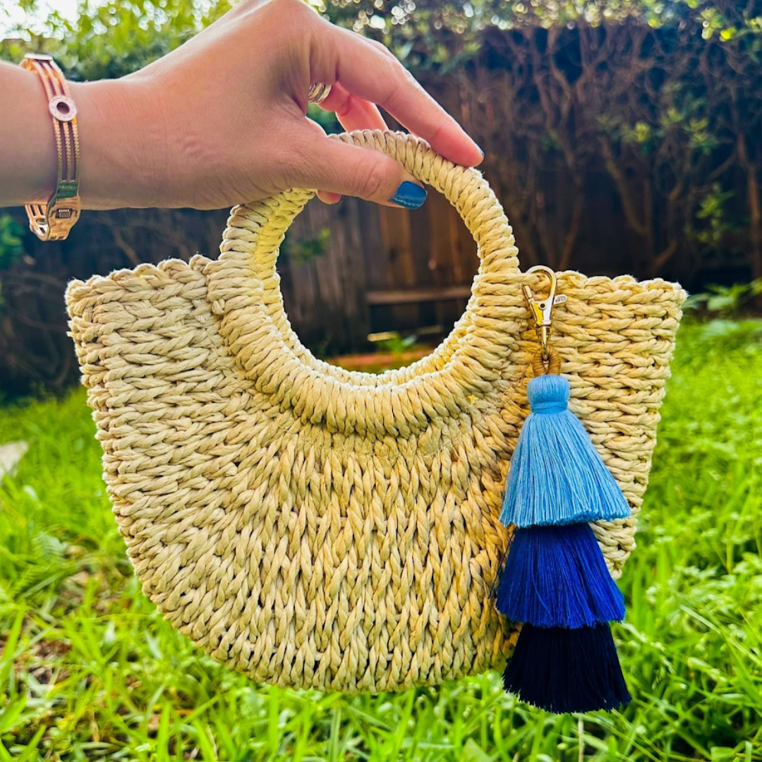 Fashionable straw bag with handles, drawstring pouch, and stylish blue ombre tassel detail.