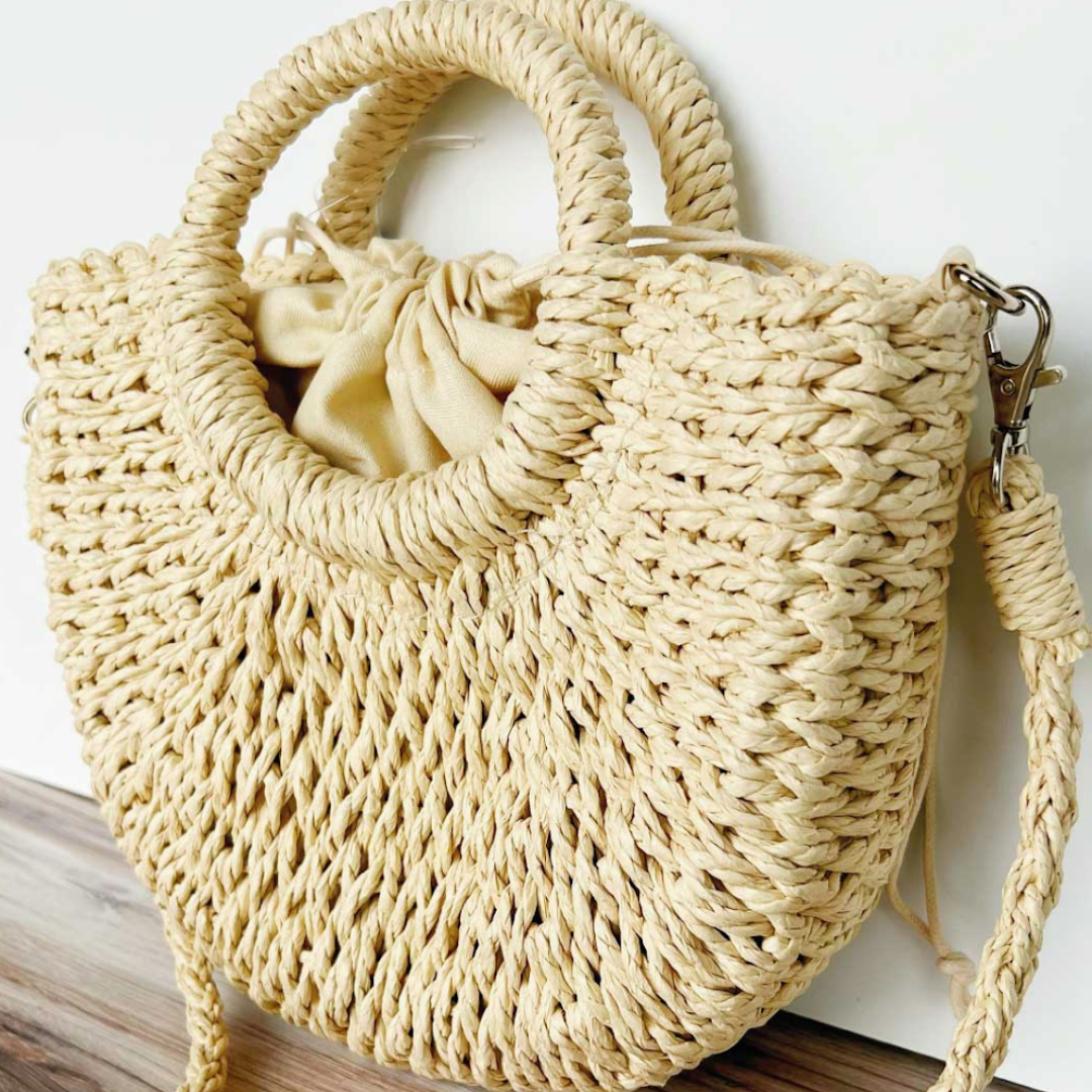 Straw beach bag with handles and detachable shoulder strap, perfect for sunny days by the shore.