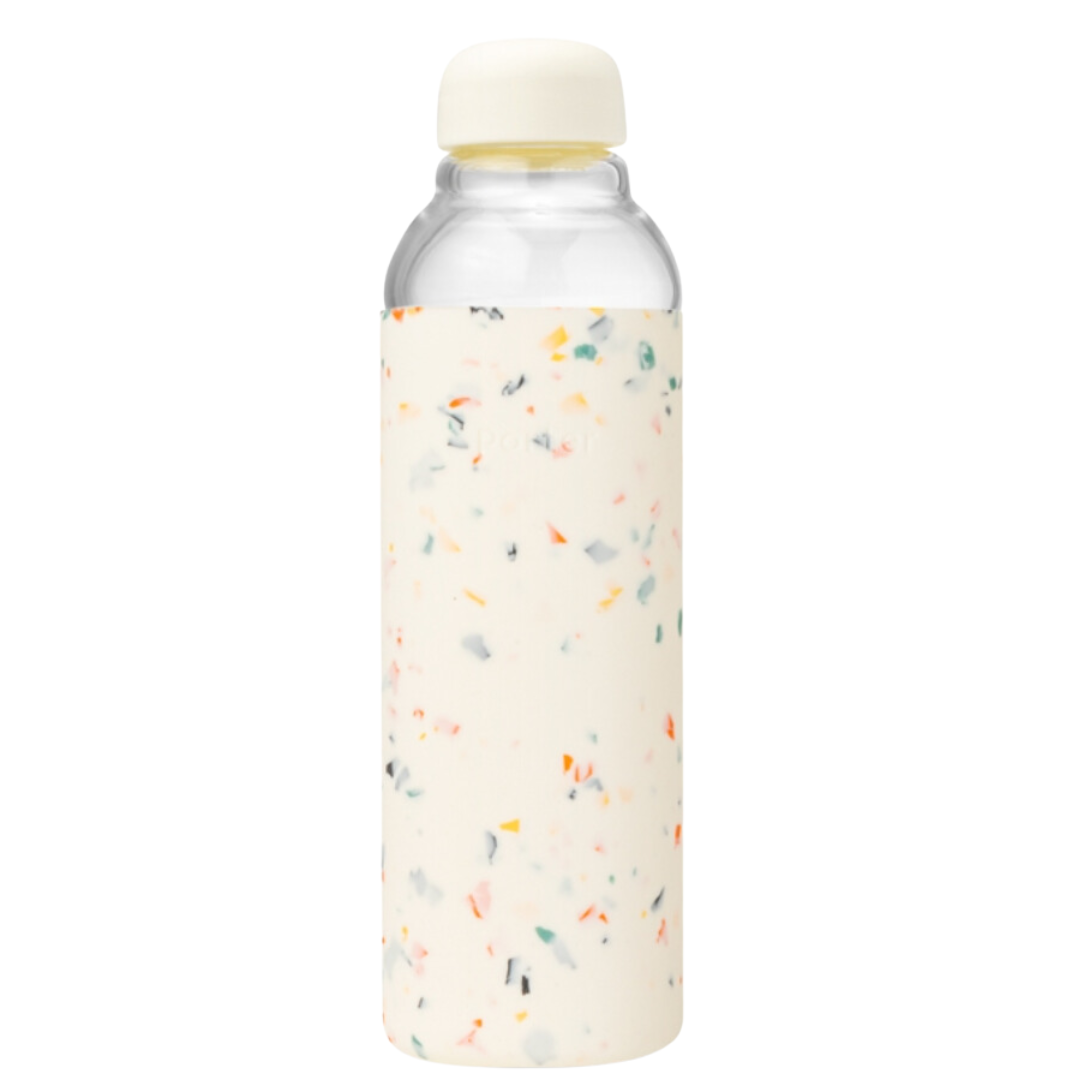 A close-up of a cream terrazzo-patterned glass water bottle with a protective silicone wrap, designed for stylish hydration on the go.