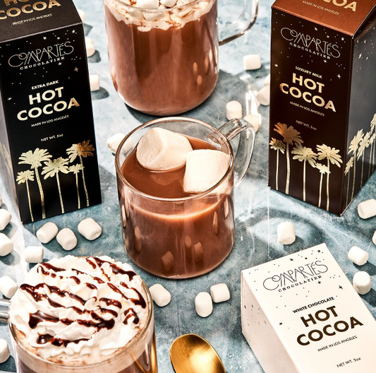 A close-up image of a stylish 5oz box of Compartes Extra Dark Hot Chocolate and a mug of cocoa, showcasing its glossy black finish and sophisticated branding.