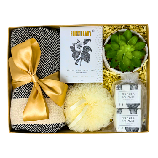 Gift set with bath items including a towel, loofah, and sea salt and lavender product in a box.