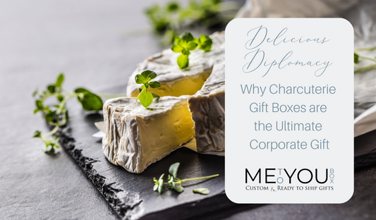 A slate charcuterie board with a round of cheese and green herbs sprinkled on top and around the board.