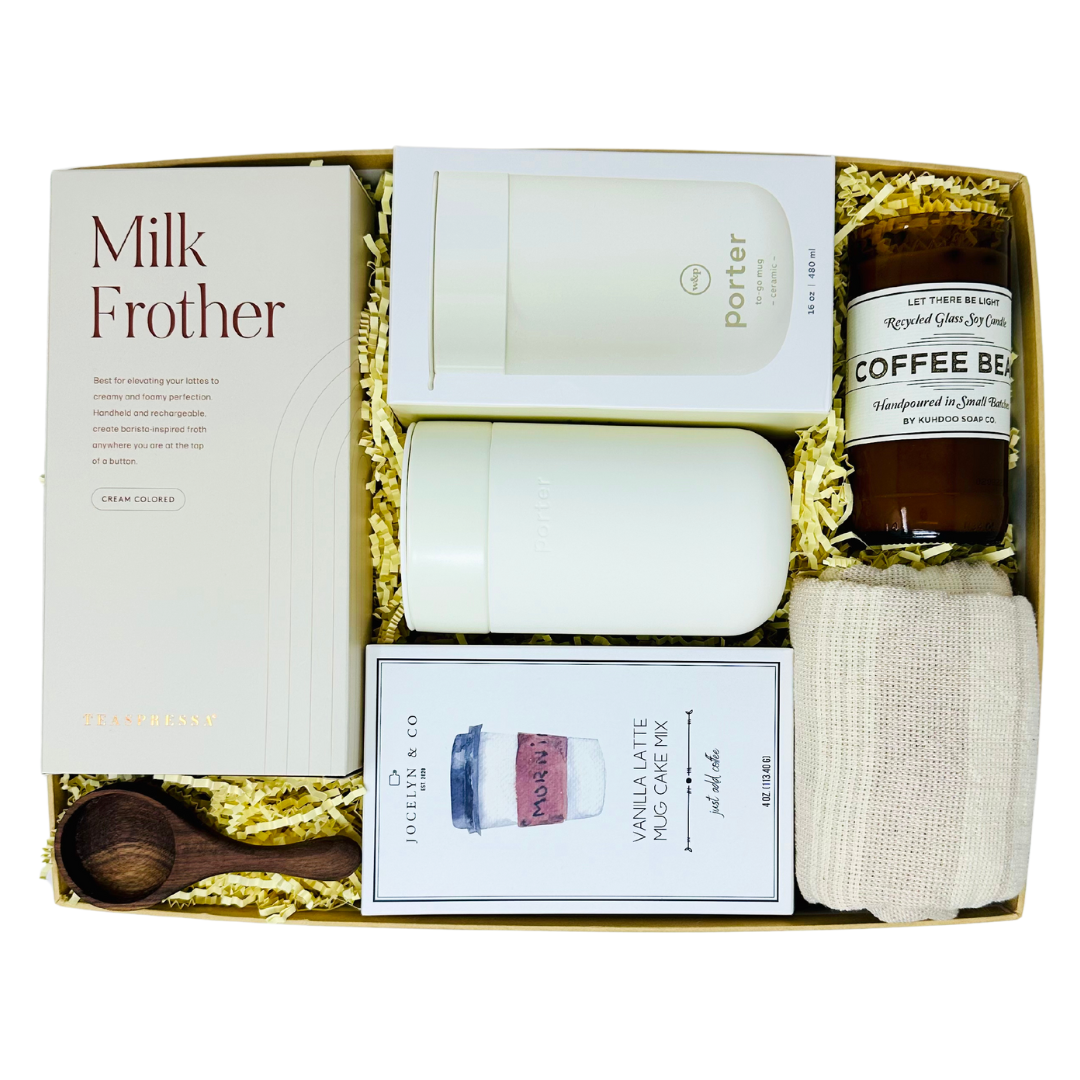 A curated 'Me To You Box' titled 'But First, Coffee,' showcasing a collection of coffee-themed gifts including a ceramic mug, gourmet latte mug cake, a milk frother, wooden coffee bean scoop, kitchen towel and a candle with real coffee beans.