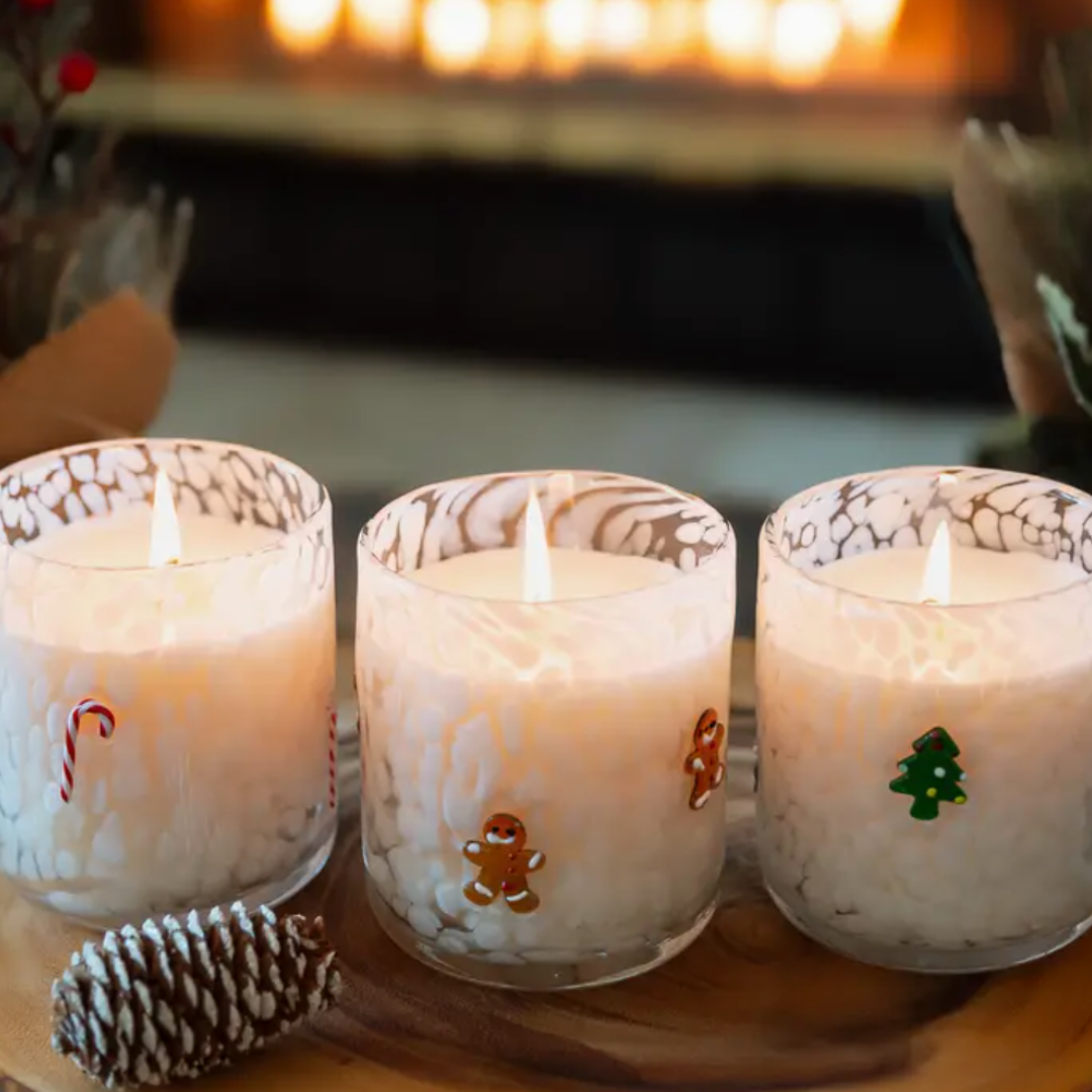 A 12oz white glass candle in a whimsical design, featuring a candy cane, a ginger bread man and a Christmas tree. This vegan and cruelty-free candle makes a charming holiday gift, and the container can be repurposed for keepsakes or other decorative uses.