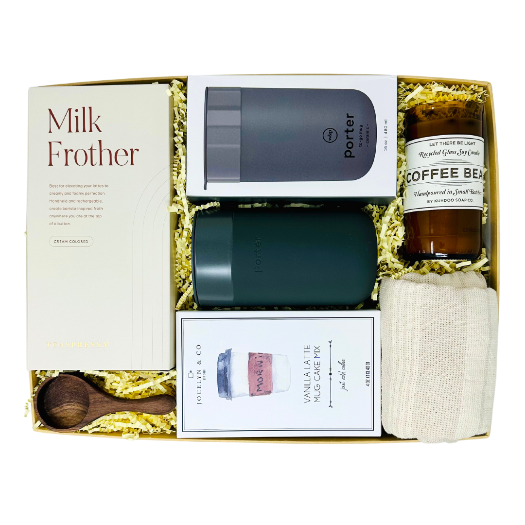A curated 'Me To You Box' titled 'But First, Coffee,' showcasing a collection of coffee-themed gifts including a ceramic mug, gourmet latte mug cake, a milk frother, wooden coffee bean scoop, kitchen towel and a candle with real coffee beans.