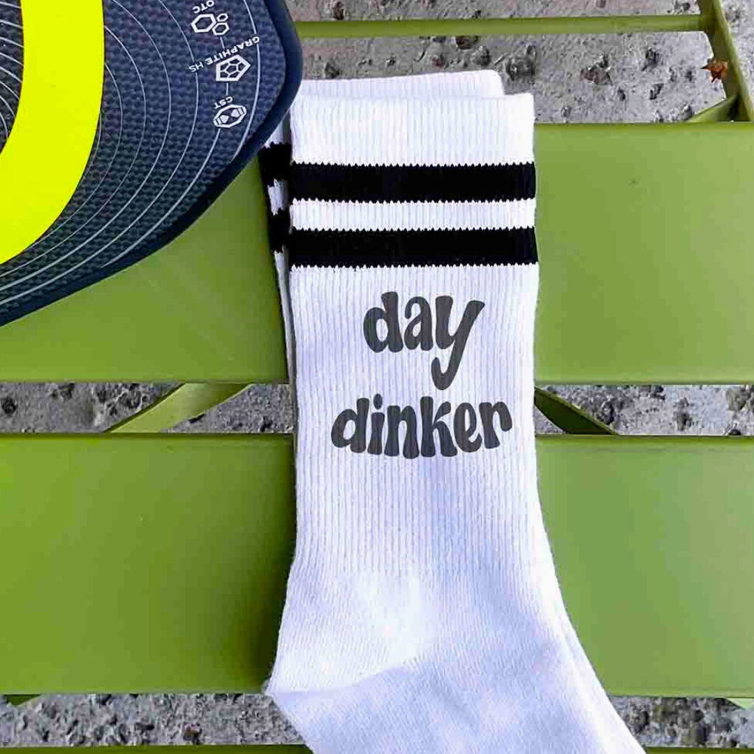 Graphic depiction of women's crew pickleball socks with the phrase 'Day Dinker', a fun addition to pickleball fashion.