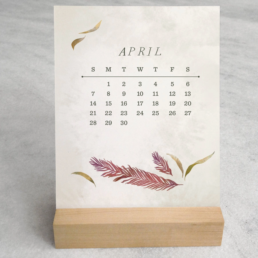 The 2025 Desk Calendar from Me To You Box, featuring 4.25" x 5.5" cards with unique monthly designs and a durable maple wood stand. This compact calendar fits perfectly on any desk, offering daily inspiration and organization with a touch of aesthetic charm.