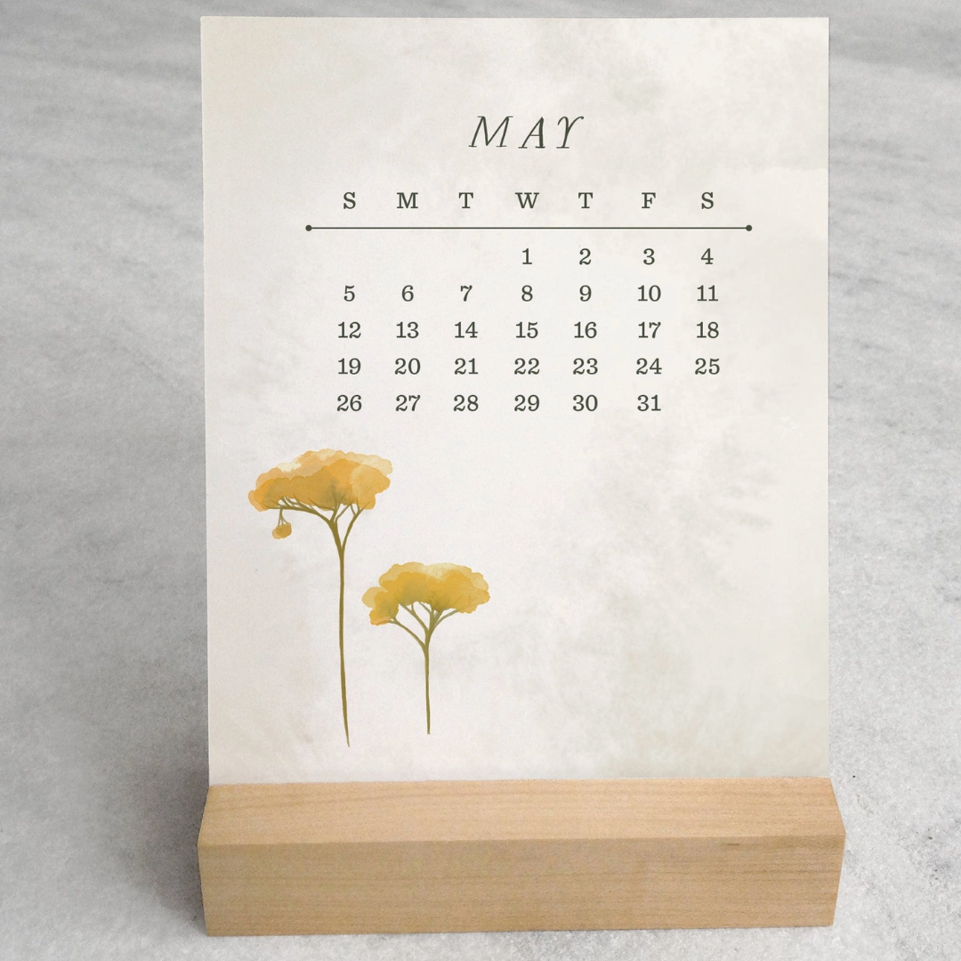 The 2025 Desk Calendar from Me To You Box, featuring 4.25" x 5.5" cards with unique monthly designs and a durable maple wood stand. This compact calendar fits perfectly on any desk, offering daily inspiration and organization with a touch of aesthetic charm.