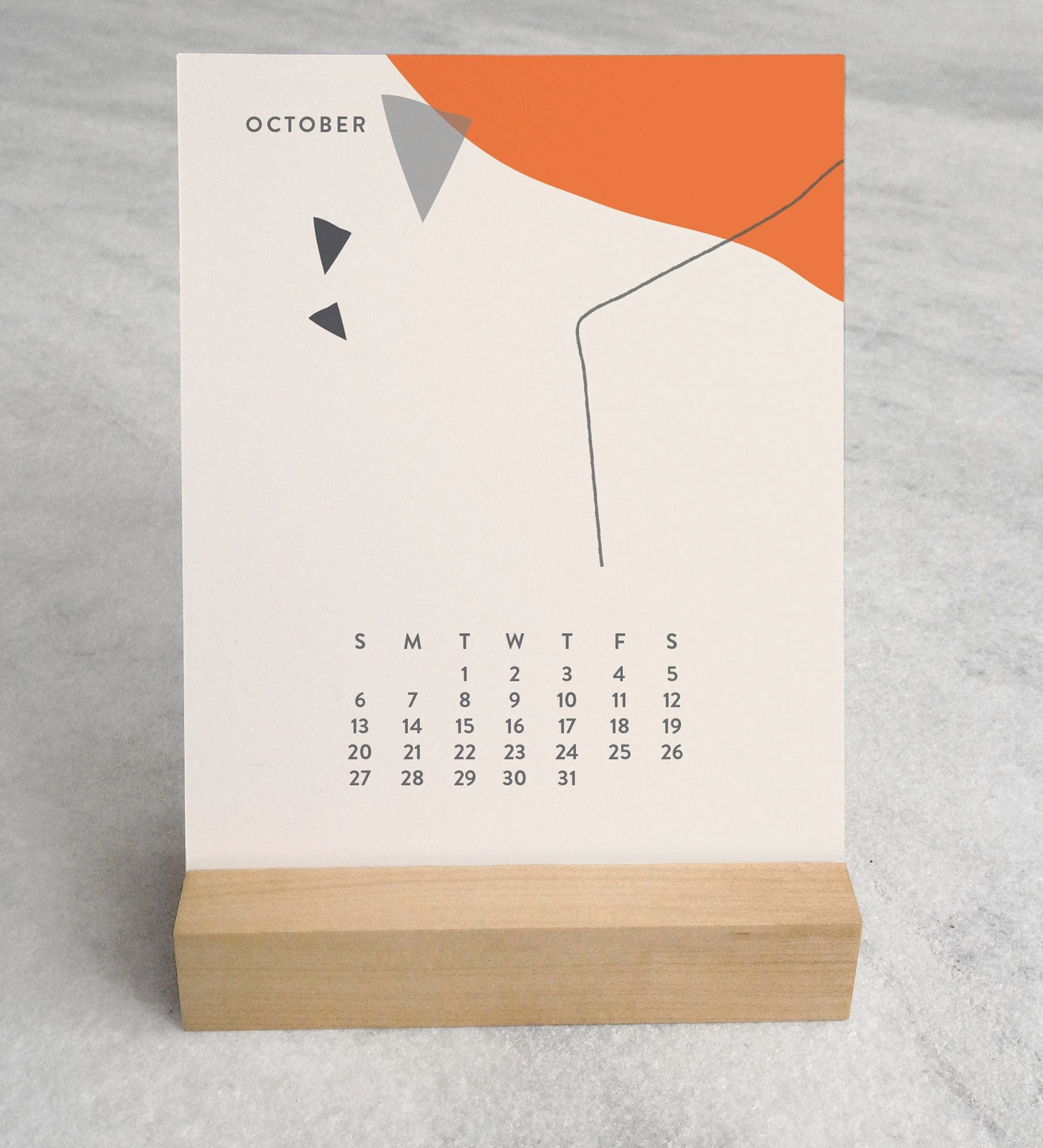 Close-up of the 2025 Desk Calendar October month with a unique monthly design visible on a 4.25" x 5.5" card. The calendar is positioned on a sturdy maple wood stand, emphasizing the quality craftsmanship. The calendar’s compact size is evident as it sits neatly on a small office desk.