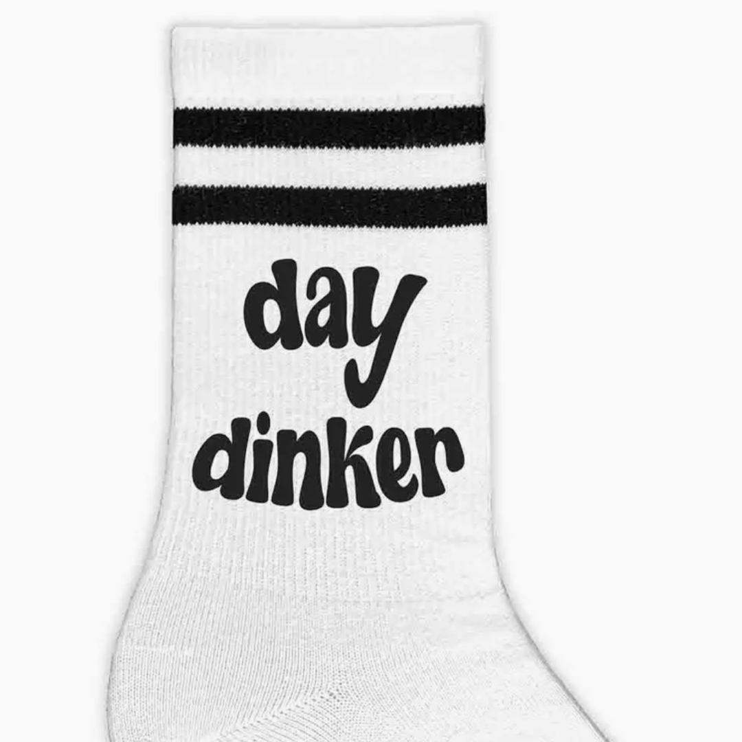 Graphic illustration of women's crew pickleball socks featuring the playful expression 'Day Dinker', ideal for pickleball lovers.