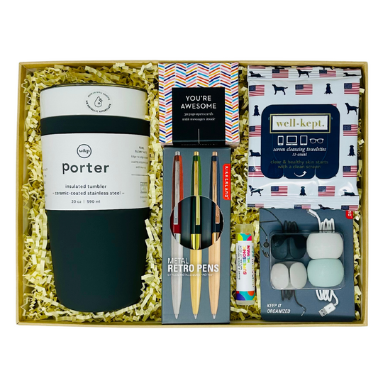A curated gift box titled 'On The Job' featuring an assortment of sleek office essentials neatly arranged. The box includes cable ties, a set of 3 premium pens, screen cleaner wipes, set of 30 pop open cards, lip balm and a chic 20oz  black silicone wrapped ceramic tumbler for coffee or tea. Perfect for professionals and remote workers, this gift box combines functionality with style to enhance productivity and elevate the work environment.