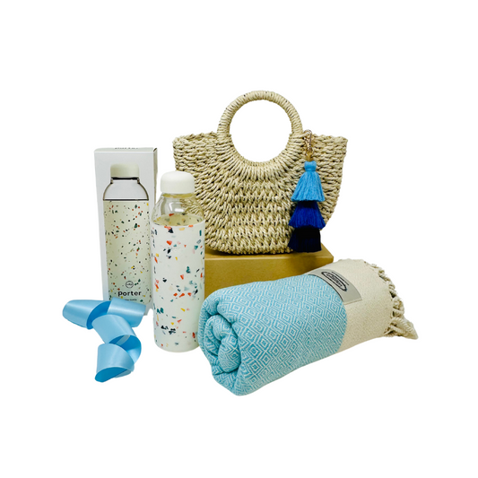 Chic beach vibes: Straw bag with blue ombre tassel, glass and silicone water bottle, & blue peshtemal towel. Fun In The Sun Me To You Box care package.