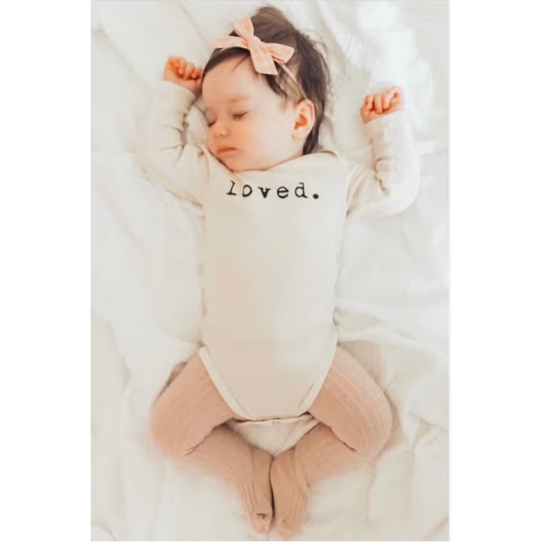 Long sleeve baby bodysuit made from organic cotton, featuring 'Loved' in black.