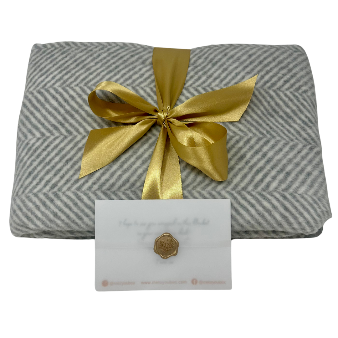Grey & white Chappywrap herringbone blanket adorned with gold satin ribbon & gift card.