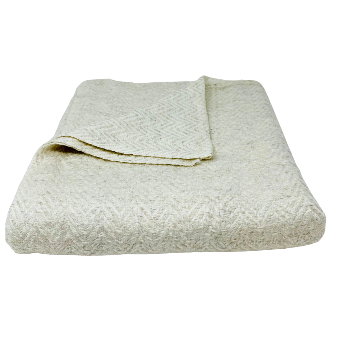 Close-up of cream cashmere blanket with soft chevron pattern, inviting coziness and warmth.