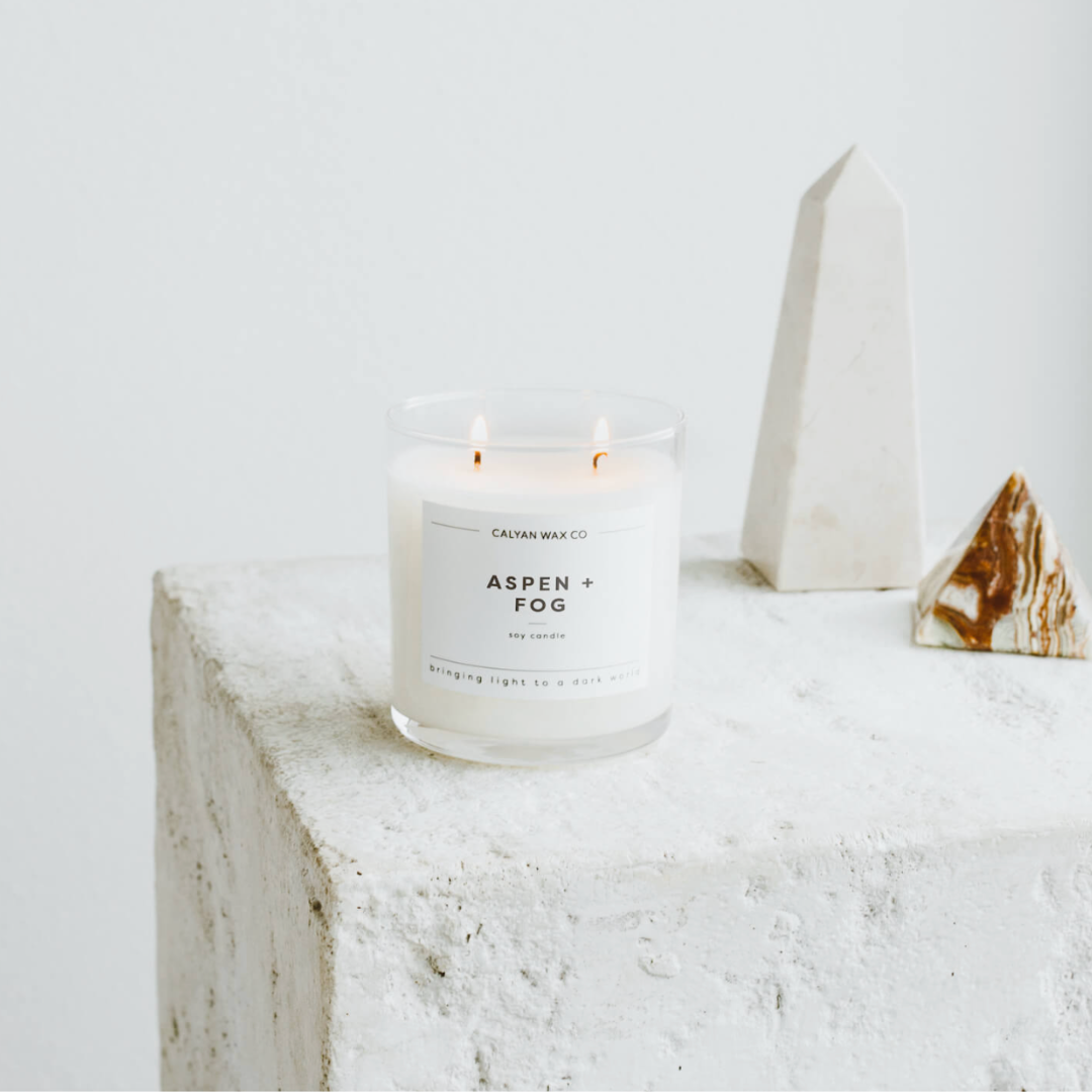 12.5-ounce soy wax candle named 'Aspen and Fog,' with a label that evokes the fresh, crisp scent of aspen trees and misty fog, designed to create a relaxing ambiance.