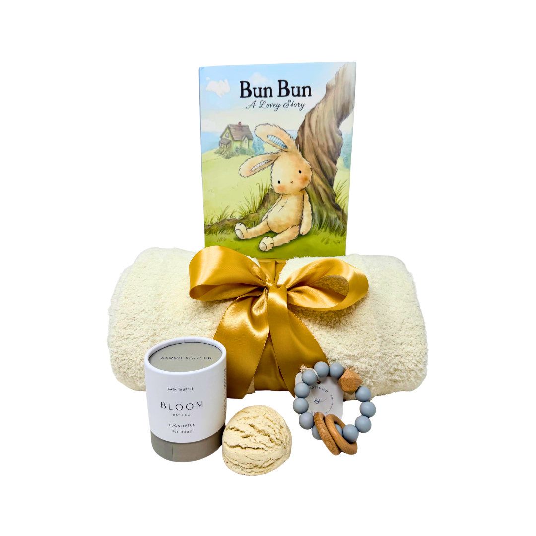 Baby gift set with blanket, rattle, bath truffle, and book on a white background.