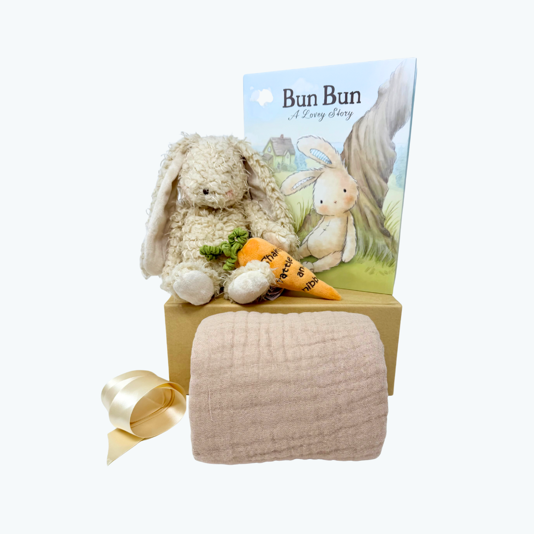Plush bunny toy with a book and blanket on a white background.
