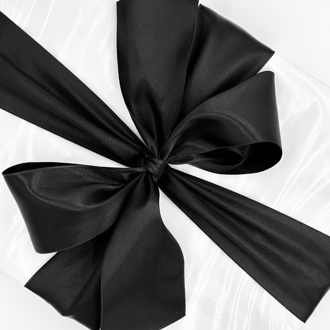 Stunning three inch black double face satin ribbon tied around a gift wrapped in white gloss wrapping paper.