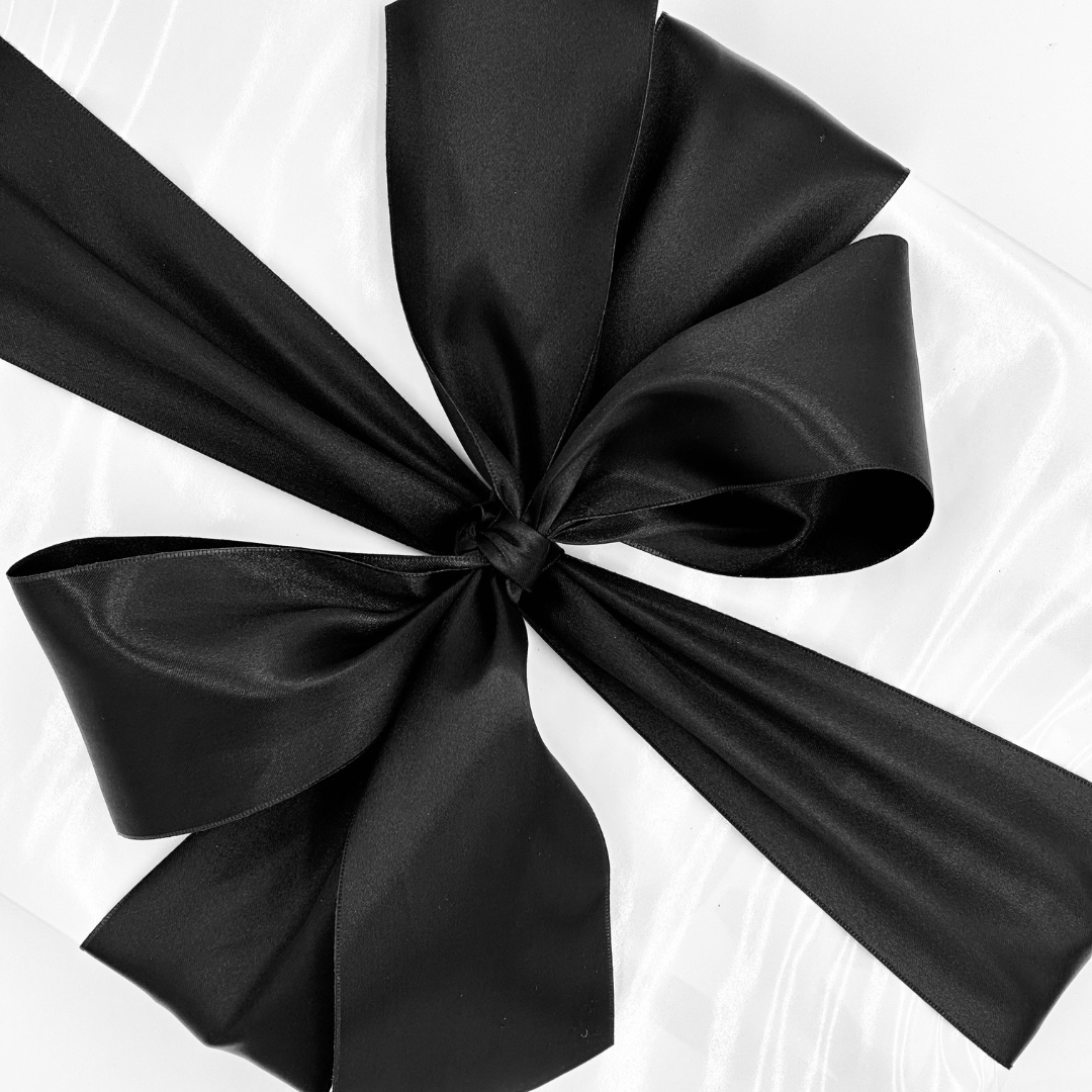 Gift wrapped in white gloss paper with black satin ribbon.