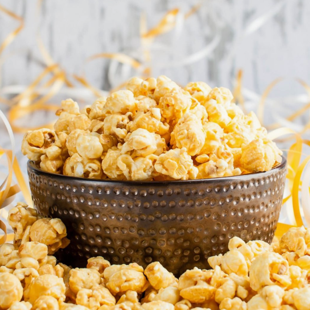 Bowl of popcorn with more popcorn around on a light background.
