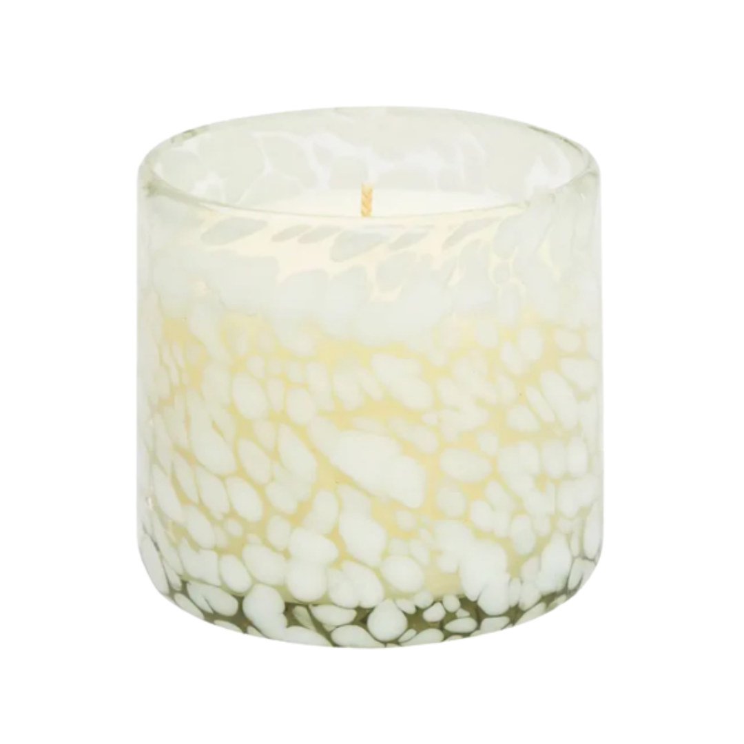 Candle in a glass container with a pebbled design on a white background