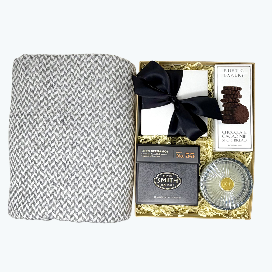 Gift set with a herringbone-patterned cashemer blanket, Smith tea, Aqua de Soi candle  and other items in a box., Rustic Bakery cookies in a decorative box.