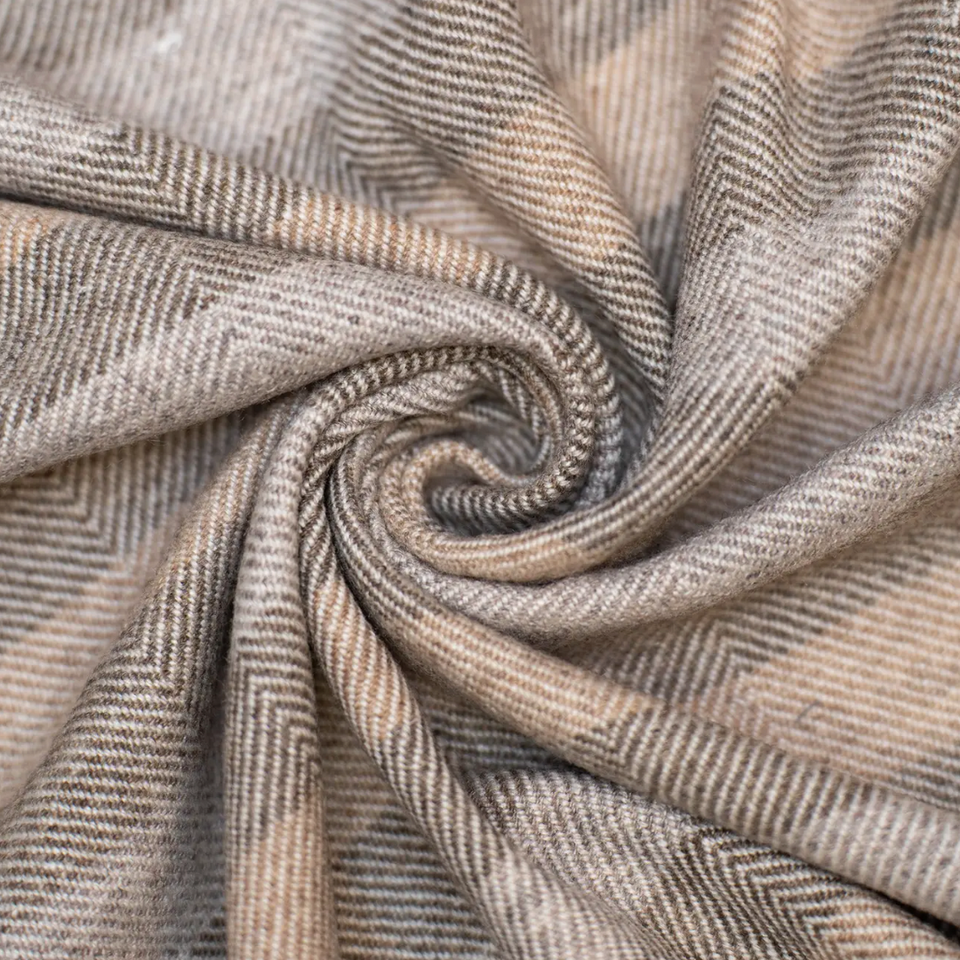 Close-up of herringbone patterned fabric in brown and beige tones.