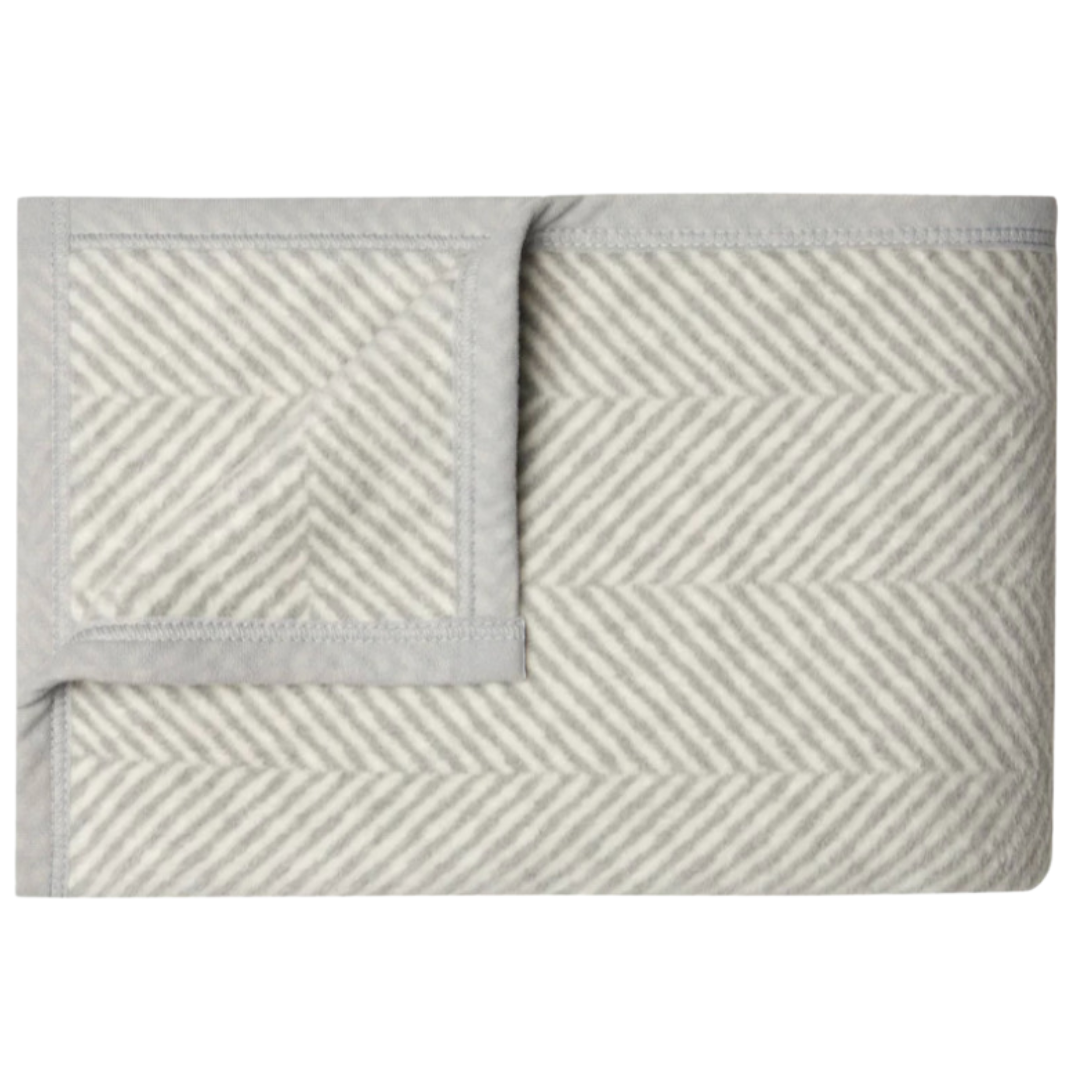 The Herringbone Blanket by Chappywrap in grey and ivory, featuring a timeless plaid design. This 40" x 60" throw is soft, durable, and machine washable, ideal for adding a cozy, stylish touch to any space.