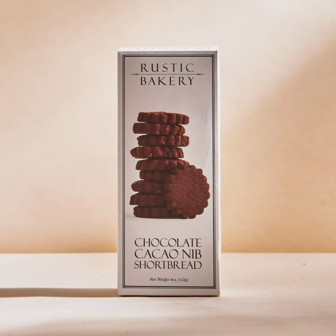 Close-up of Rustic Bakery Chocolate Cacao Nib Shortbread cookies, showcasing their rich texture with visible cacao nibs and a light dusting of fleur de sel. This indulgent treat combines buttery flavor with a hint of cocoa, perfect for chocolate lovers.