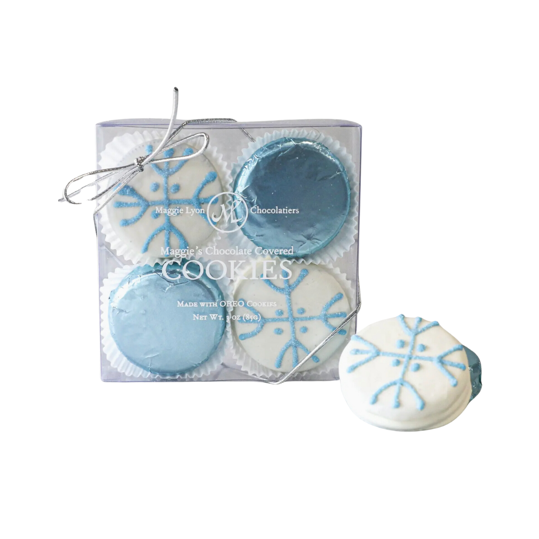 A set of four milk and white chocolate-covered cookies, each adorned with a charming snowflake design. The cookies are high-quality Oreo cookies coated in a rich blend of milk and white chocolate. The elegant packaging highlights the artisanal quality and festive decoration of the cookies, which are crafted by Maggie Lyon Chocolatiers, a family-owned confectionery company. Ideal for gifting or personal enjoyment, these cookies combine traditional craftsmanship with gourmet indulgence.