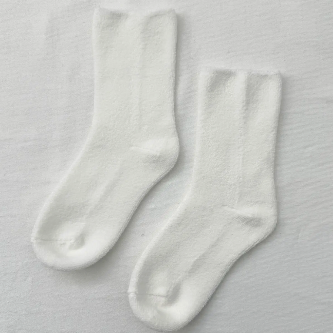 Close-up of fluffy white socks with a ribbed design, offering a snug and cozy fit for relaxing at home.