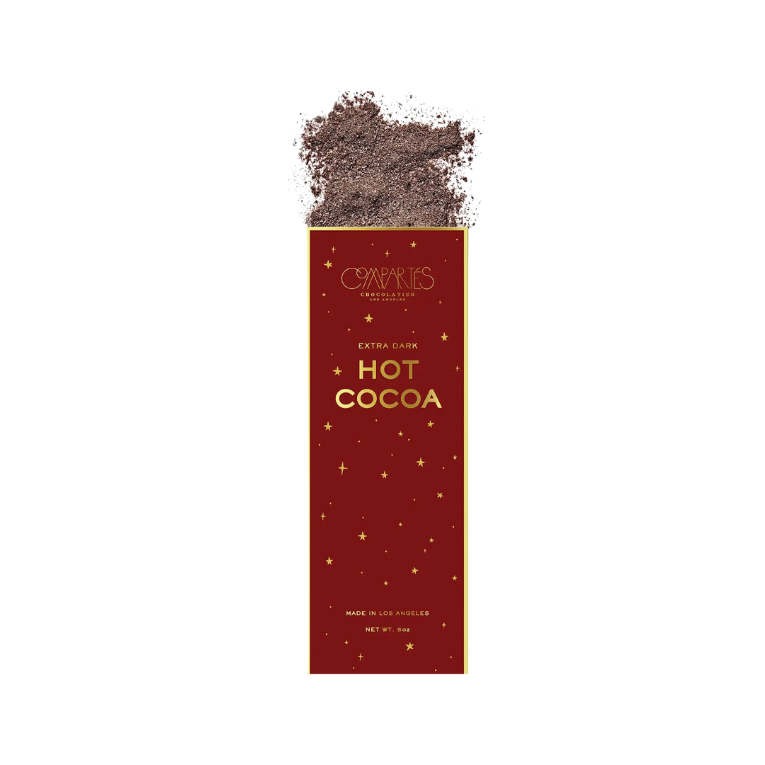 A luxurious gold foil package of Compartés EXTRA DARK HOT COCOA MIX, featuring an elegant starry night design, celebrated as the best in America by Travel & Leisure and USA Today. The 5oz handmade product is proudly crafted in Los Angeles.