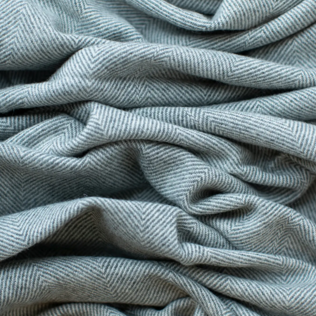 Grey and White textured blanket draped over a wooden chair in a cozy living room setting.