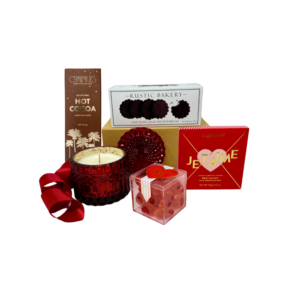 Decorative red candle with a ribbon, hot cocoa mix, and other items on a white background