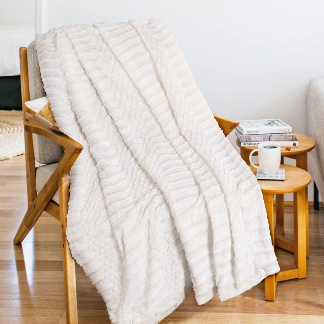 White textured blanket draped over a wooden chair in a cozy living room setting.