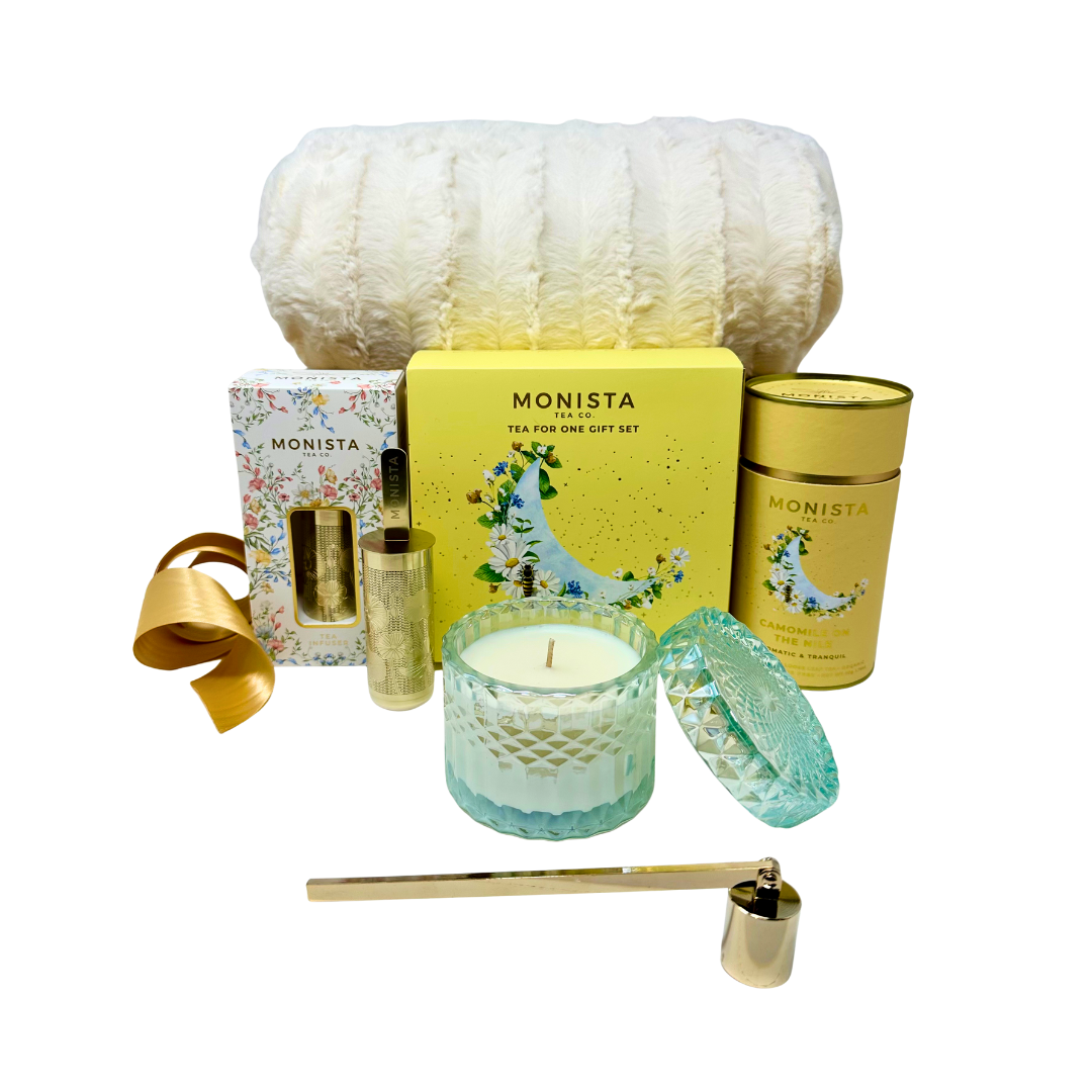 Gift set with Monista tea, candle, and other decorative items on a white background