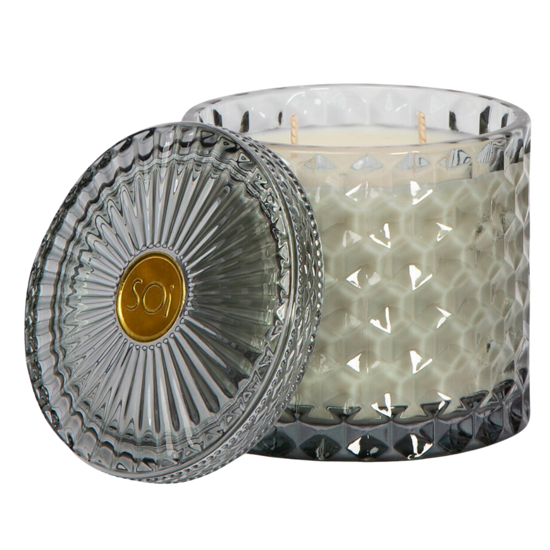 Aqua de Soi's Heathered Suede Shimmer Candle is a 15oz double wick soy wax candle in a beautiful grey cut glass vessel. The diamond-cut glass makes this candle a luxurious addition to any space. Filled with 100% all natural, food-grade kosher soy oil, that burns cleaner and up to 40% longer than paraffin, wax or traditional soy blend candles. Heathered Suede Glass Shimmer Candle has scents of Brushed Suede, Oakmoss Embers &amp; Palo Santo. Approximately a 55 hour burn time.