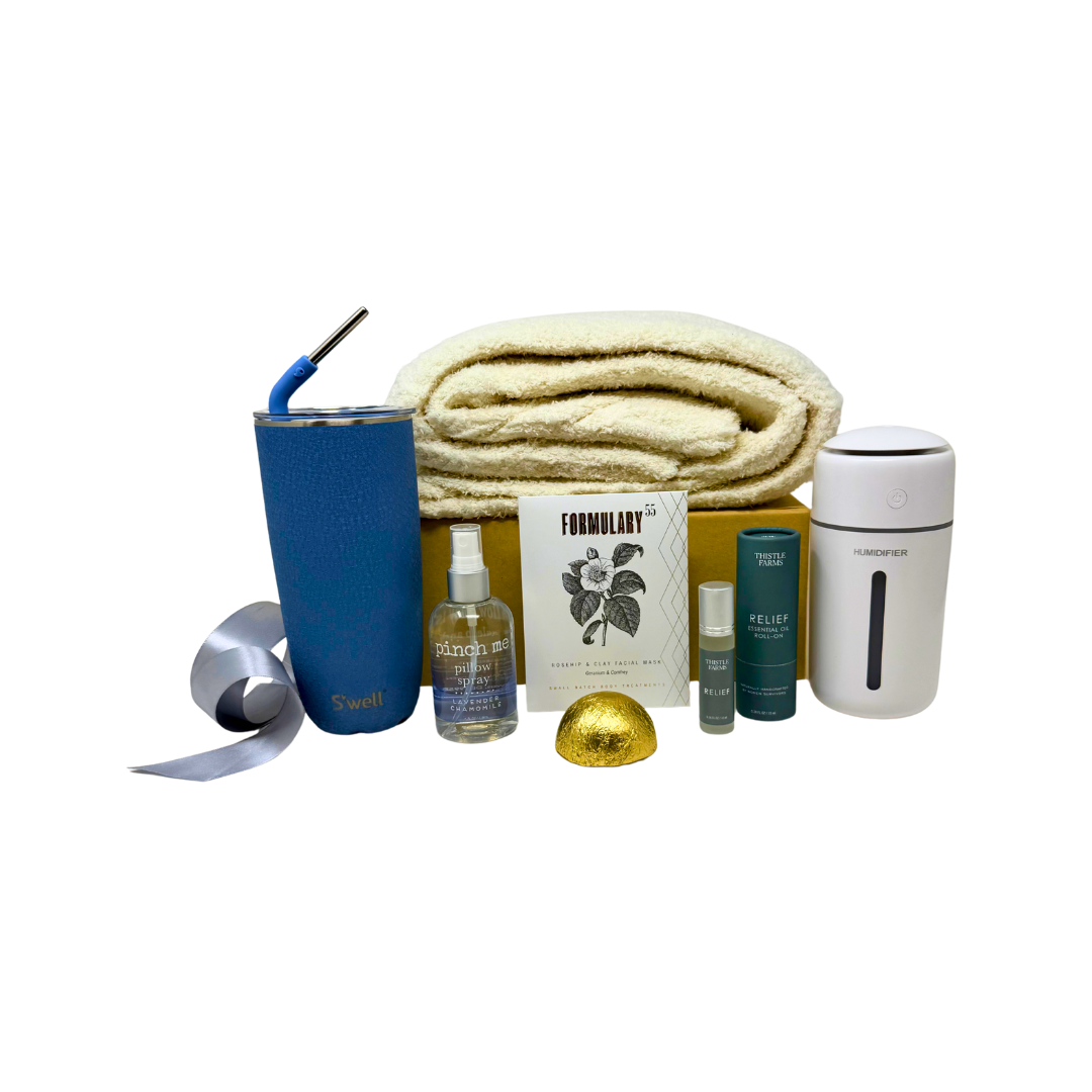 Collection of items including a blue tumbler, blanket, and skincare products on a white background