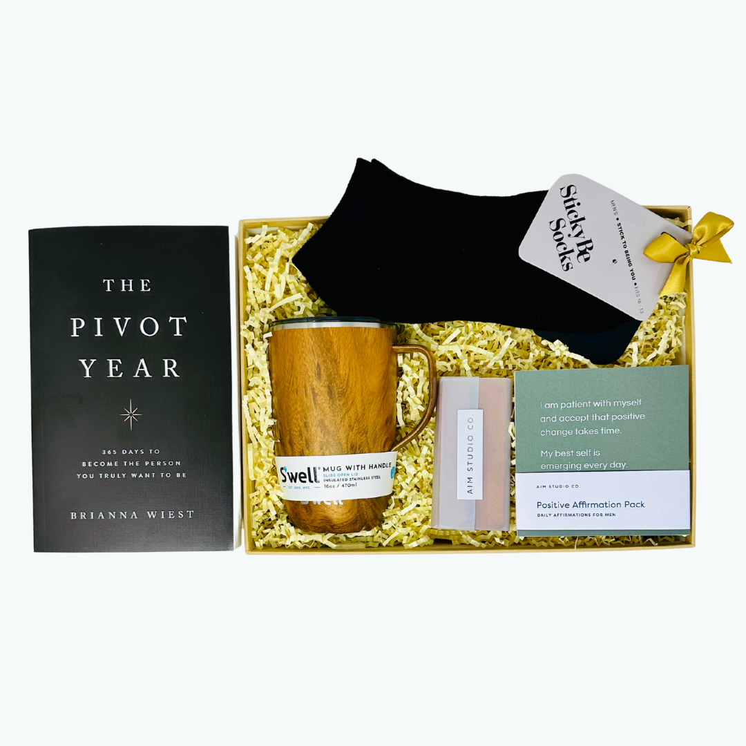 Gift set with S'well mug, Pivot Year book, inspirational cards, and socks in a box on a white background.