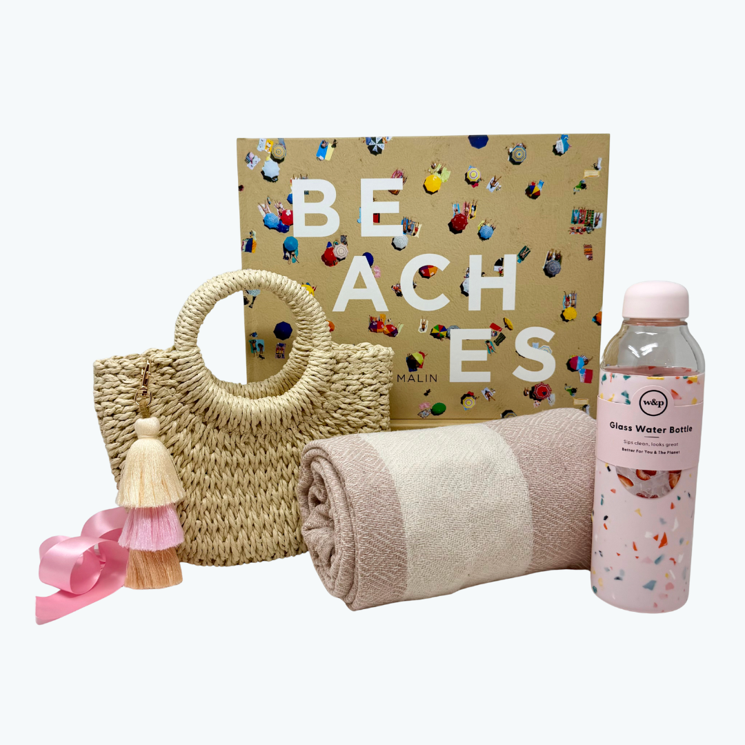 Beach-themed items including a woven bag, towel, and water bottle with a 'Beaches' book in the background.