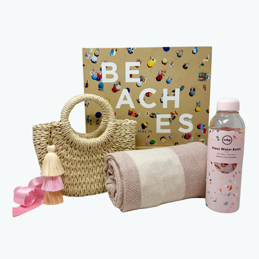 Beach-themed items including a woven bag, towel, and water bottle with a 'Beaches' book in the background.