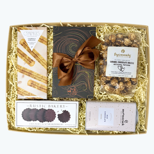 Gift box with snacks and treats including cookies, chocolate bars, hot chocolate tin, and popcorn.