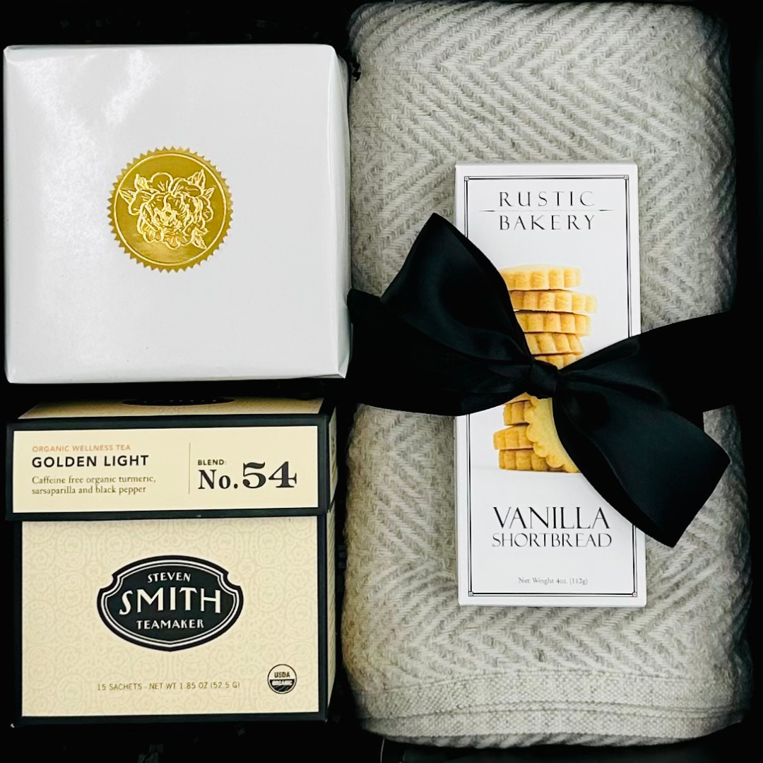 Gift set with tea boxes, a blanket, and a bakery product.