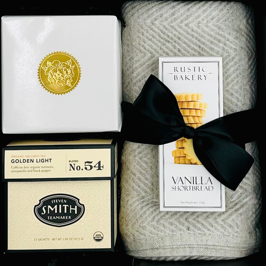 Gift set with tea boxes, a blanket, and a bakery product.