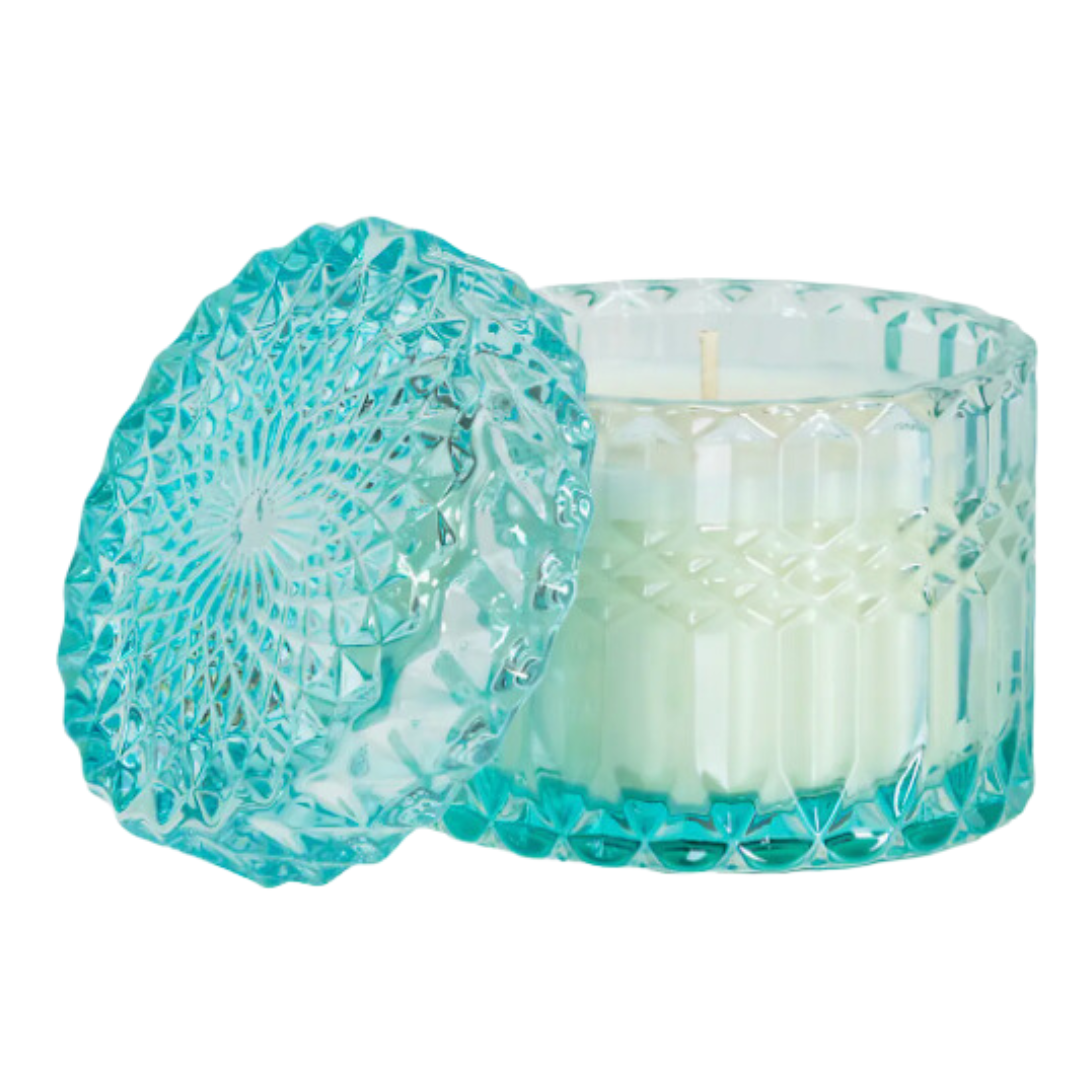 The Shimmer Candle from the Aqua de Soi collection, featuring an 8-ounce soy wax design in diamond-cut glass, radiating elegance. It has a Tropical Breeze scent with notes of Yuzu and Tiger Lily, evoking sun-soaked beaches, and offers 45 hours of burn time.