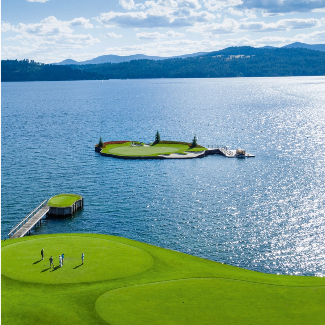 Golf course with a lake and mountains in the background.