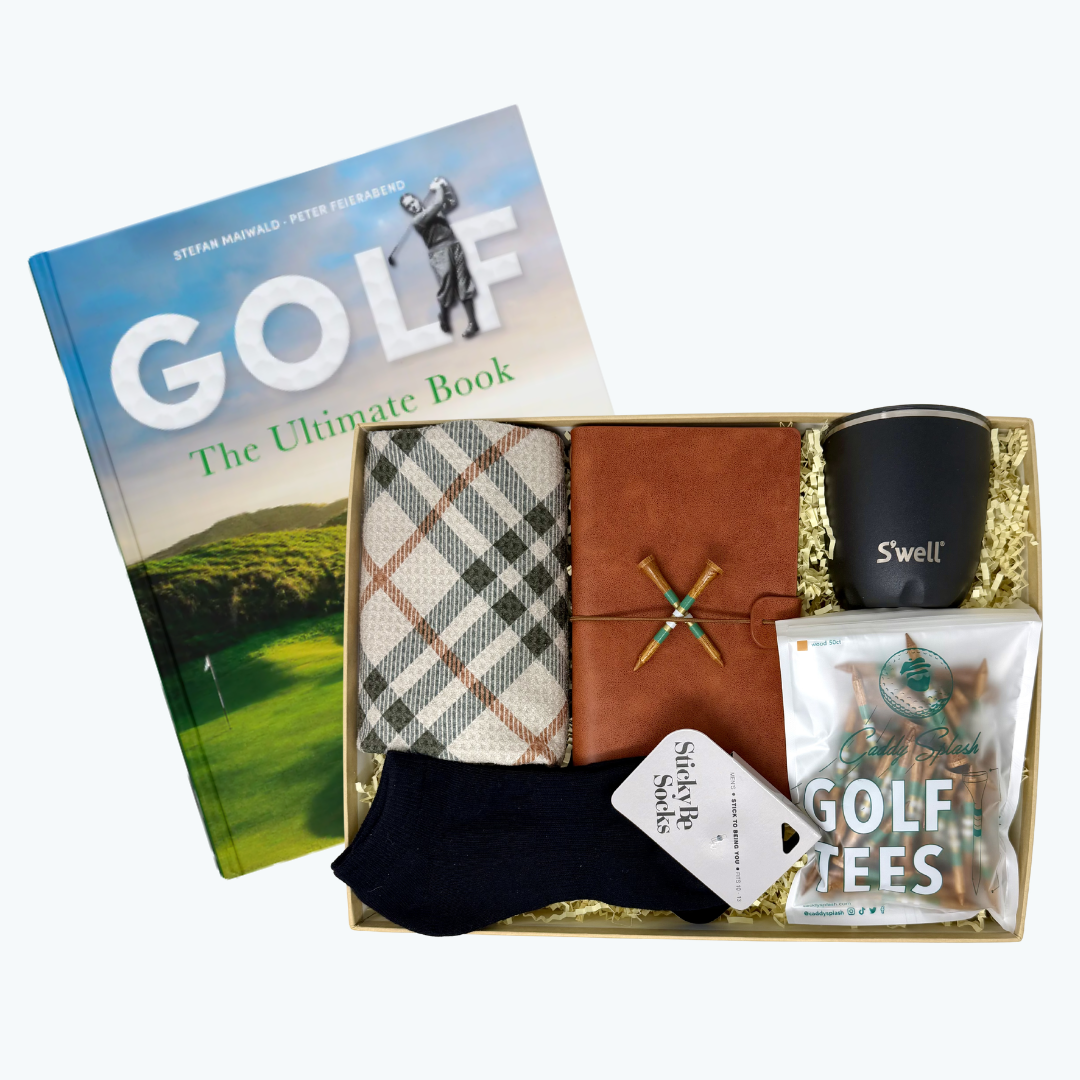 Gift box with golf-themed items including a book, tumbler, socks, golf tees, golf towel and golf journal on a white background