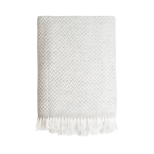Soft, ethically sourced cashmere blanket in a timeless grey and white herringbone design, 56 by 90 inches. This handmade piece offers both warmth and elegance, ideal for gifting or home decor.