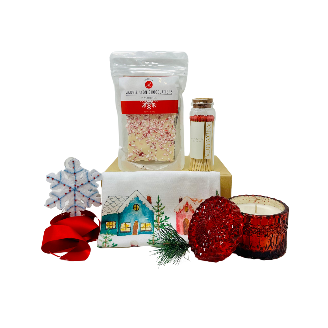 A festive "HAPPY HOLIDAYS" curated Me To You Box, showcasing its contents. The box includes an elegant beaded snowflake ornament, Maggie Lyon Chocolatiers Peppermint Bark, a Colorful Cottages Holiday Kitchen Towel, a Holiday Spice Glass Soy Wax Candle, and a set of wooden matches in a cork-topped glass jar. The items are arranged to highlight the holiday cheer and warmth each piece brings, with the box emphasizing the joy of giving and the charitable aspect supporting Julia's Butterfly Foundation.